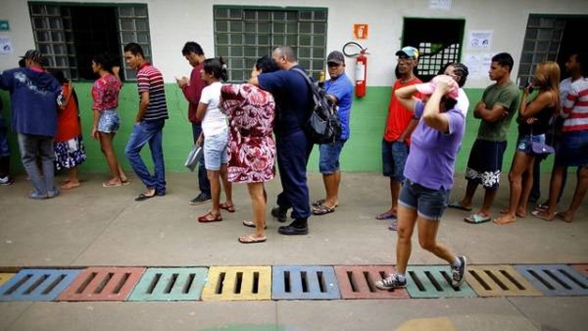 Un grupo de personas forma una fila en un puesto de votación en la favela Estrutural, en Brasilia, durante la segunda vuelta de las elecciones presidenciales.