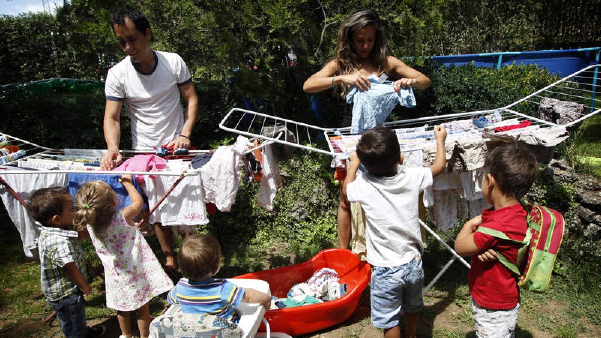 Los cinco hijos de Lorena Castellanos y Raúl Santos ayudan a tender la ropa en el jardín de su casa.