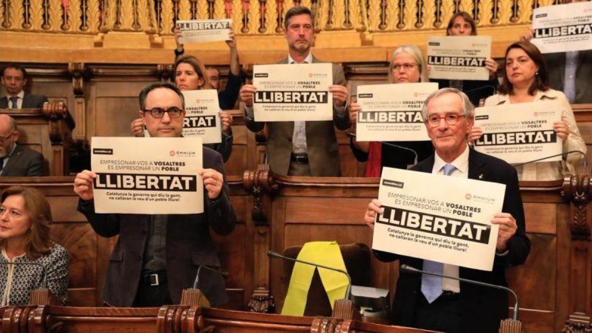 Los concejales del PDECat en Barcelona muestran carteles pidiendo la libertad de los encarcelados. Con un lazo amarillo, el lugar que ocupaba el exedil y exconseller Joaquim Forn.