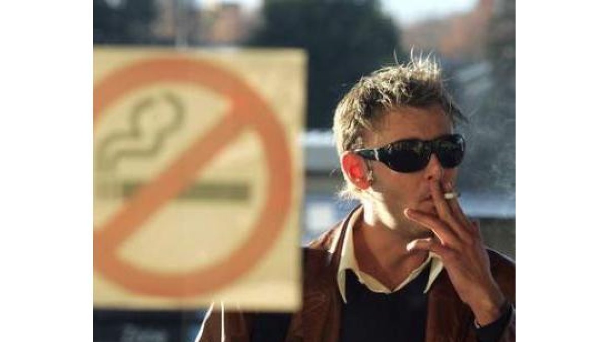 Un hombre fuma un cigarrillo en el exterior de un bar