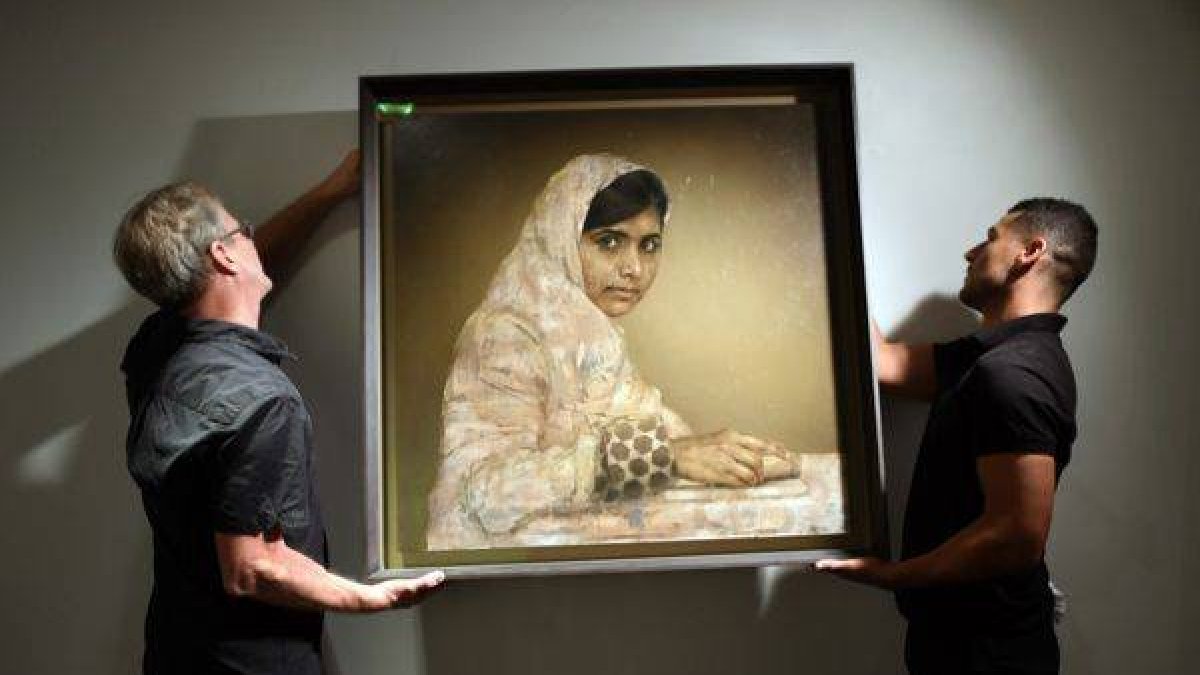 Dos trabajadores cuelgan el retrato de Malala 'Niña leyendo', de Jonathan Yeo, antes de la subasta, el miércoles en Nueva York.