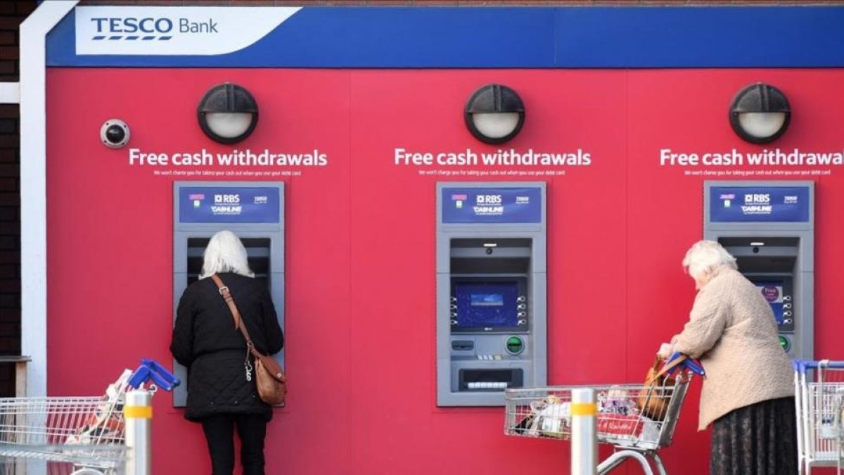 Dos mujeres retiran efectivo de cajeros automáticos de Tesco Bank en Liverpool.