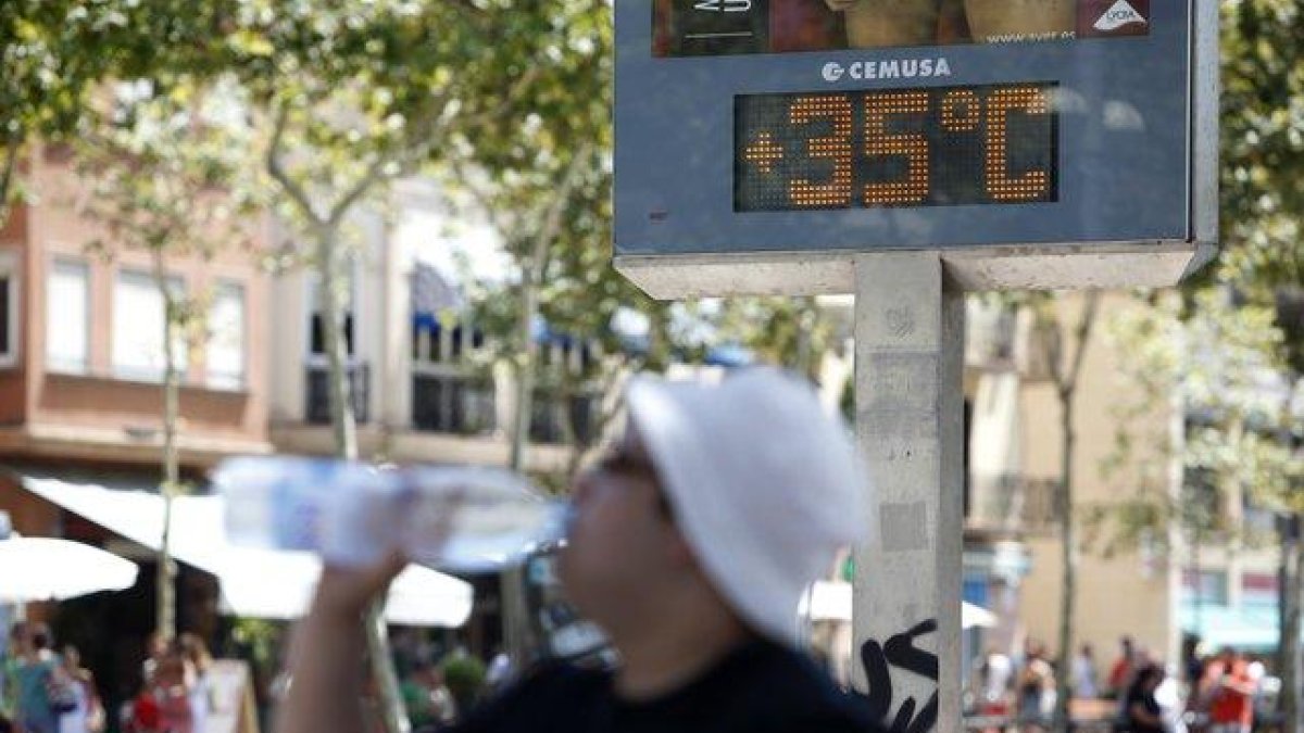 Un hombre bebe agua ante un termómetro que marca los 35 grados, en una imagen de archivo.