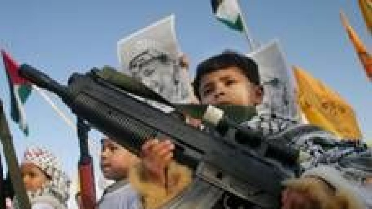 Varios niños palestinos recorren las calles con armas de juguete contra del muro