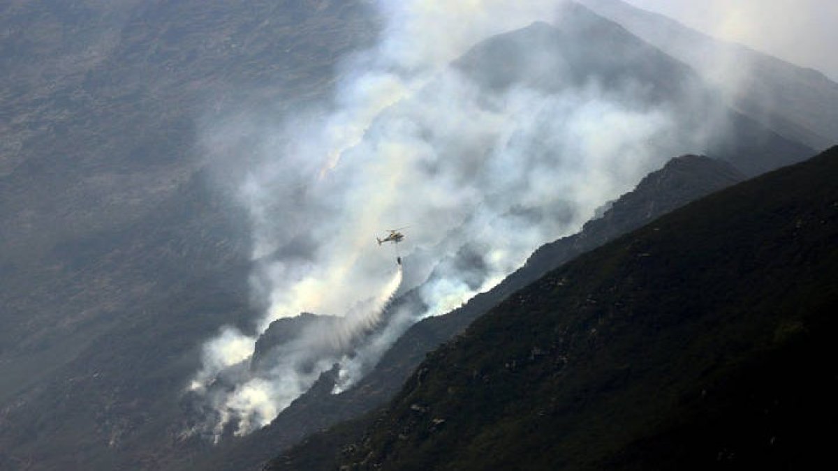 Un helicóptero se aproximaba ayer a la zona de Peñalba de Santiago donde la orografía hacía imposible el trabajo de las cuadrillas de tierra. ANA F. BARREDO