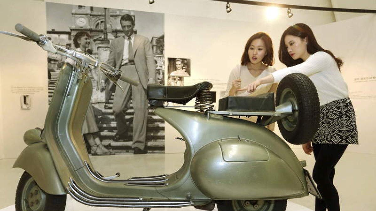 De izquierda a derecha,  el cuerpo de carteros de Barcelonan; el modelo que  condujo Audrey Hepburn en ‘Vacaciones en Roma’; varias motos en Wittenbergplatz, en Berlín; El actor alemán Mario Adorf y excursionistas en Manzanares del Real.