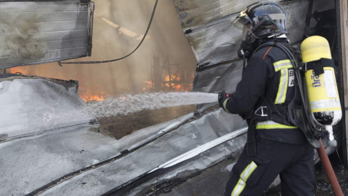 Un bombero del Ayuntamiento de León sofoca un incendio en una nave de Valverde de la Virgen. MARCIANO PÉREZ