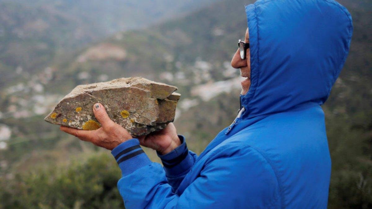 Un lugareño sostiene una piedra de pizarra, el mismo material con que ha topado la perforación del túnel vertical para el rescate de Julen en Totalán (Málaga).