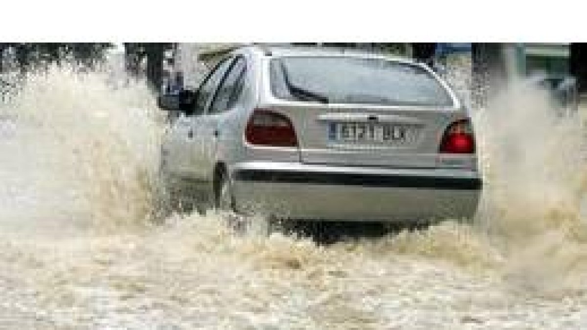 Un automovilista atraviesa una gran balsa de agua en una calle del barrio de Los Remedios