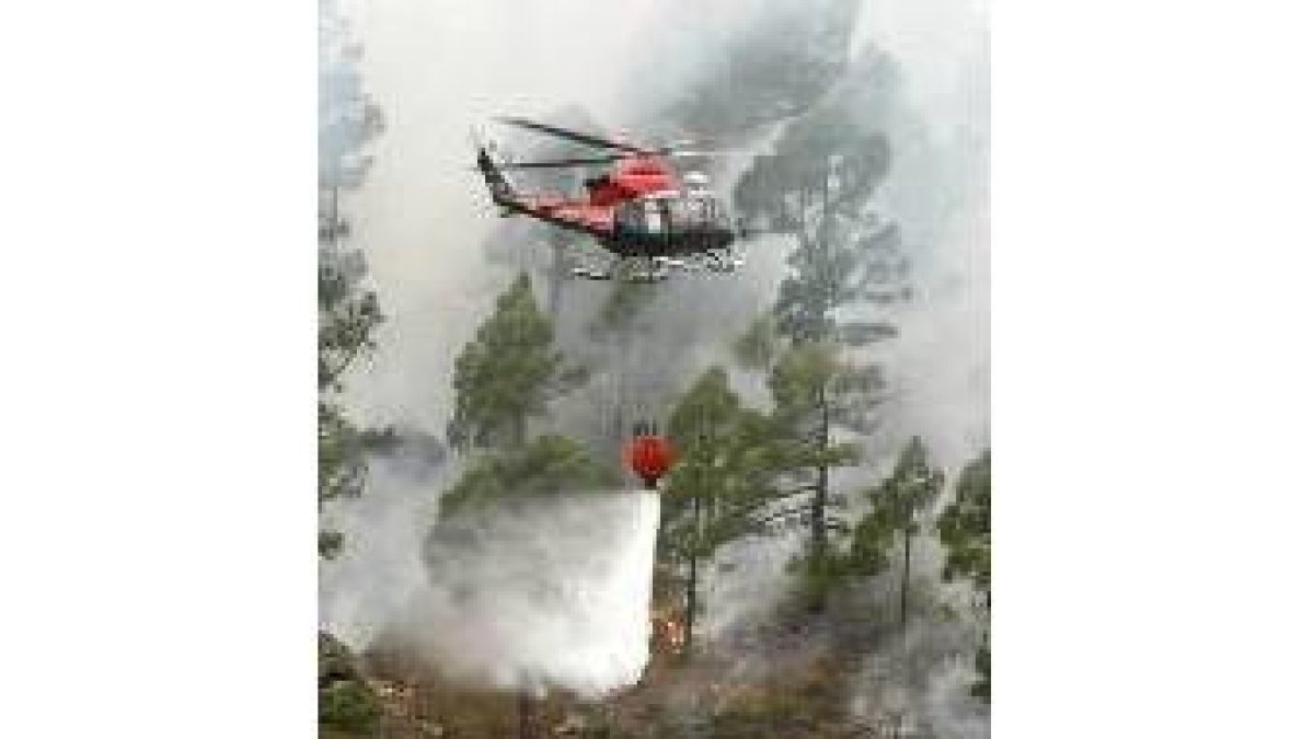 Un helicóptero arroja agua durante las labores de extinción del incendio
