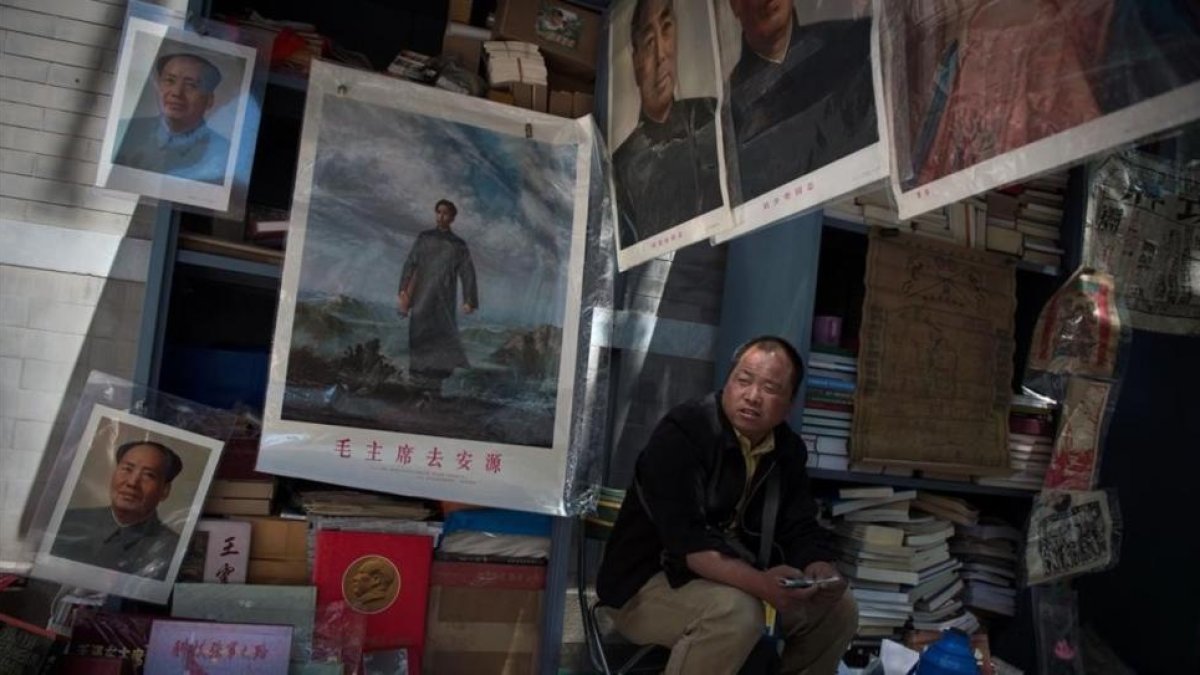 Un comerciante espera la llegada de clientes para vender imágenes y recuerdos de Mao Zedong.
