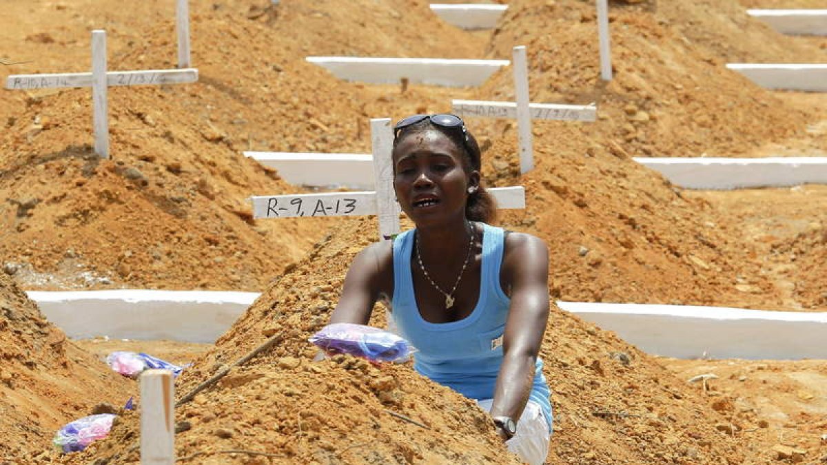 Una mujer llora en la tumba de su hermano, fallecido por el ébola en Liberia