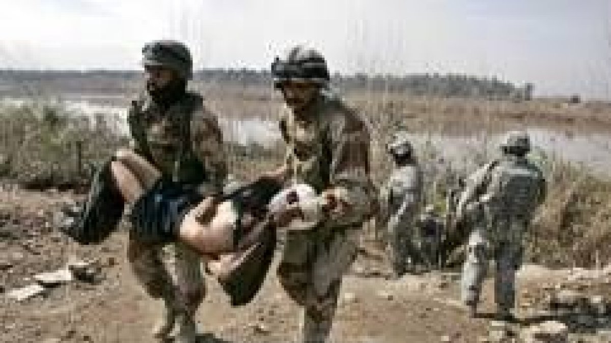 Soldados iraquíes evacúan a un niño herido por disparos norteamericanos en la orilla del río Tigris
