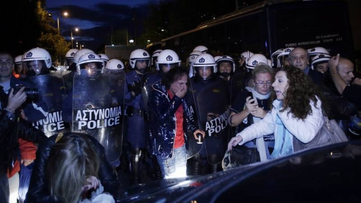 Trabajadores de la TV pública griega reaccionan a los gases lacrimógenos lanzados por la policía, esta madrugada, en los alrededores de la ERT, en Atenas.