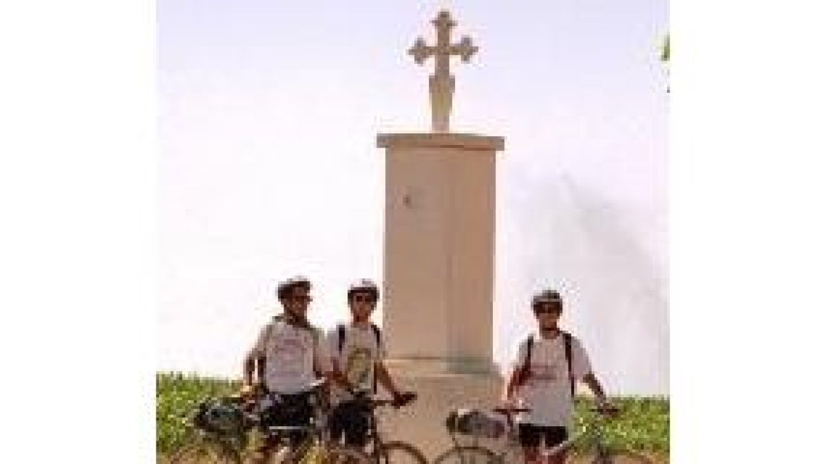 Tres ciclistas junto al monolito erigido en memoria de Millán Bravo