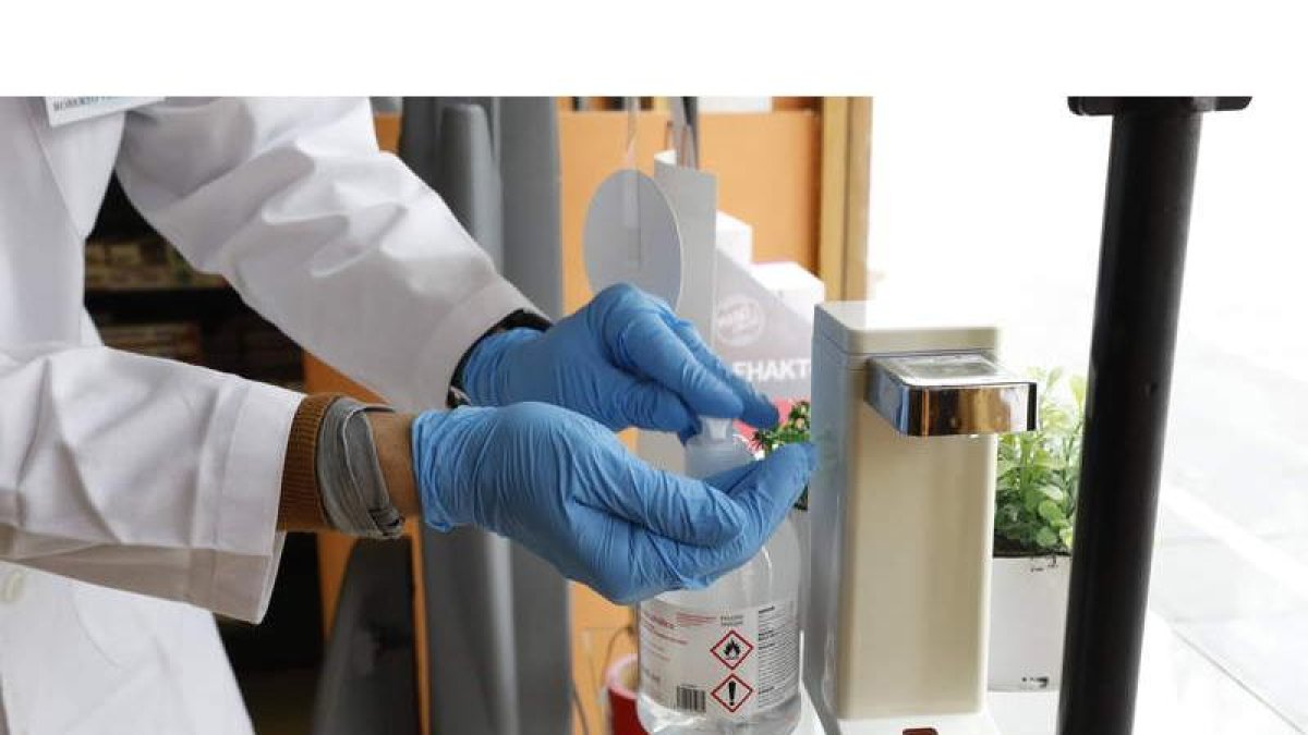 Una farmacéutica se aplica gel en los guantes para eliminar posibles contactos con superficies infectadas con covid. MARCIANO PÉREZ