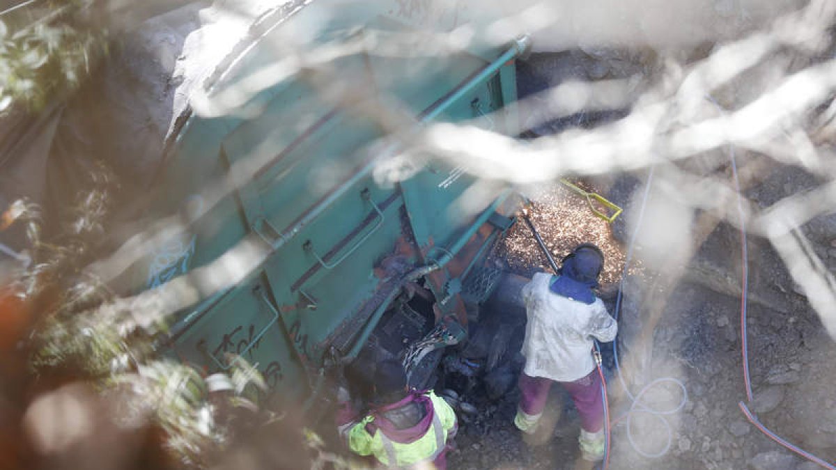 Dos operarios trabajaban ayer en desprender vagones empotrados para deshacer el amasijo del tren accidentado. MARCIANO PÉREZ