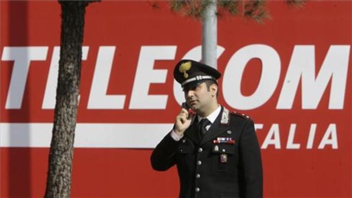Un policía habla con su móvil frente a la sede de Telecom Italia en Rozzano