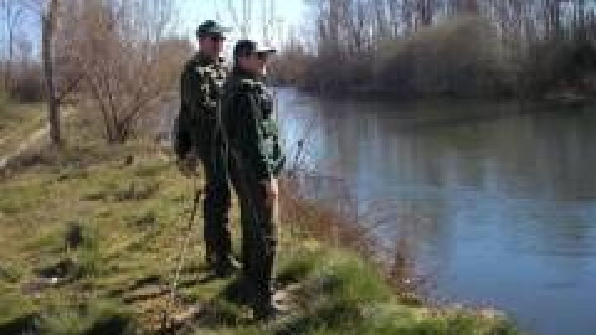 Dos aficionados observan cómo baja el río, muy alto y canoso, en el coto de Marne