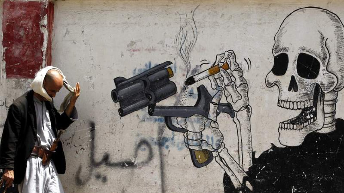 Un hombre camina junto a un grafiti antitabaco en Saná (Yemen).  YAHYA ARHAB