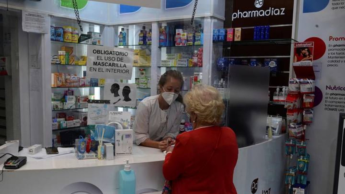 Una vecina del distrito del Puente de Vallecas compra en una farmacia en la Avenida de la Albufera en Madrid. VÍCTOR LERENA