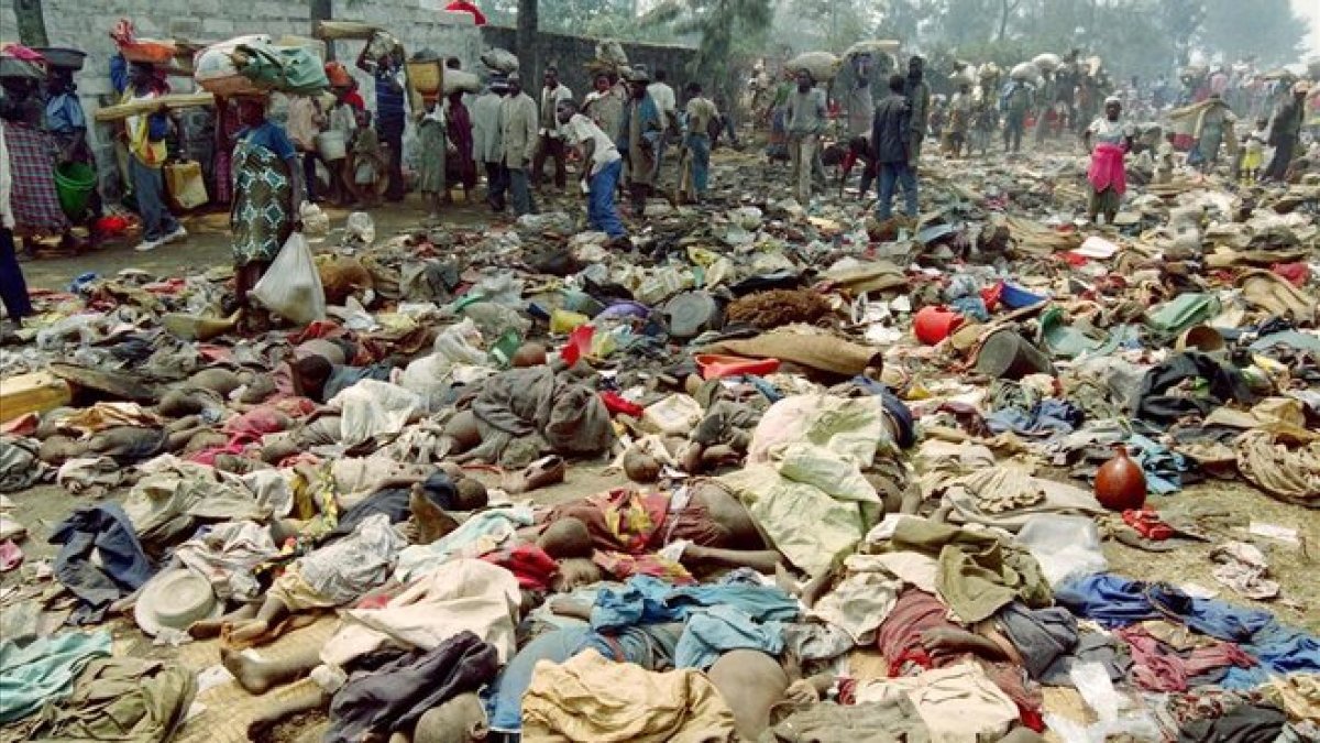 Refugiados ruandeses pasan junto a los cuerpos sin vida de cientos de compatriotas asesinados en la frontera con Zaire el 18 de julio de 1994.