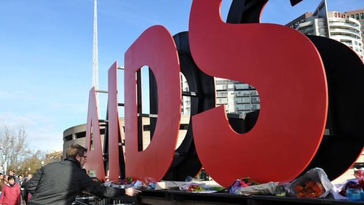 Un hombre coloca flores ante un cartel de la conferencia internacional del sida, el domingo en Melbourne.