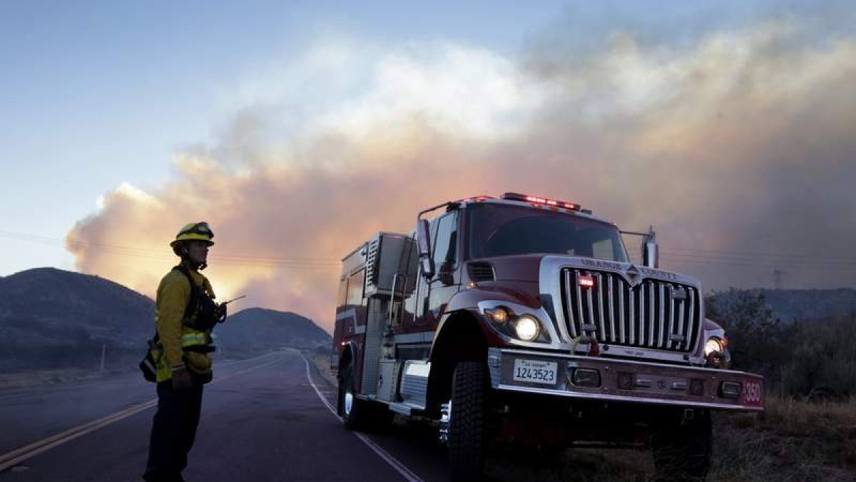 Un bombero vigila una carretera junto al incendio forestal a 115 km de Los Ángeles. PAUL BUCK