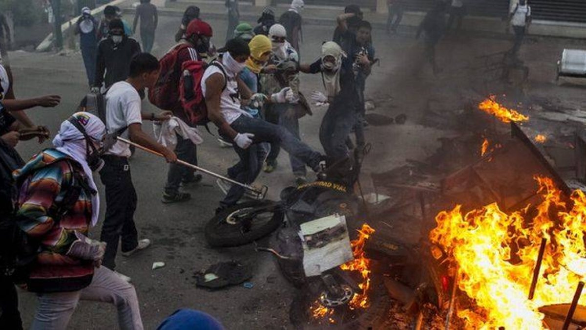 Manifestantes se enfrentan a los antidisturbios, anoche en la plaza Altamira, en Caracas.