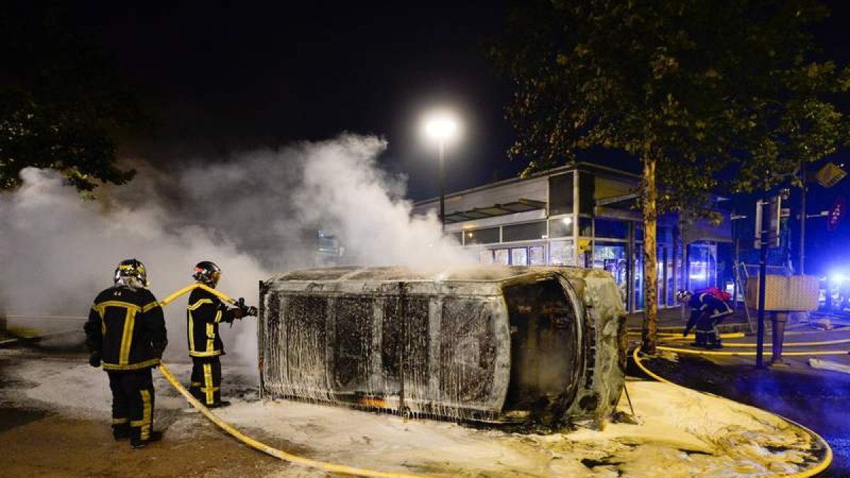 Los bomberos trabajan en la extinción de un coche durante los disturbios en Nantes. FRANCK DUBRAY