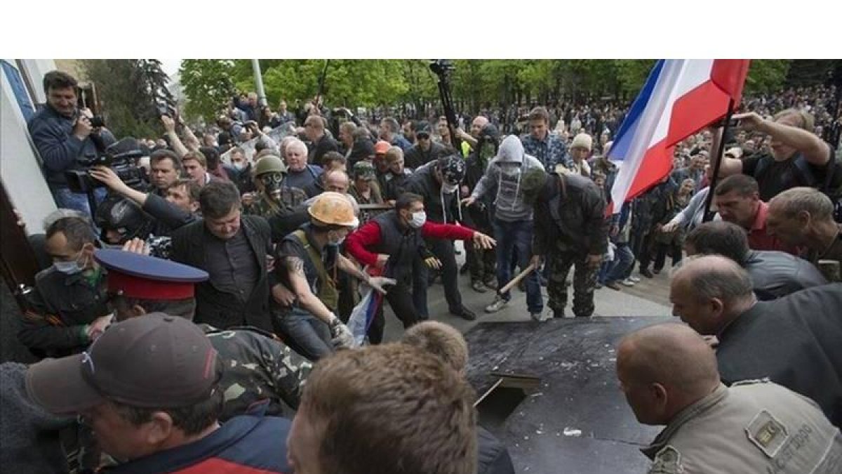 Activistas prorrusos se disponen a asaltar un edificio de la Administración regional, este martes, en Lugansk.