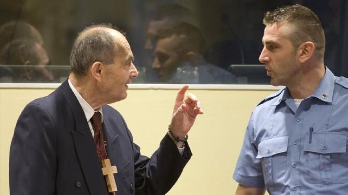 Tolimir (izq), condenado por la masacre de Srebrenica, habla con un guardia de seguridad de la ONU en el tribunal de La Haya, el pasado 8 de abril.