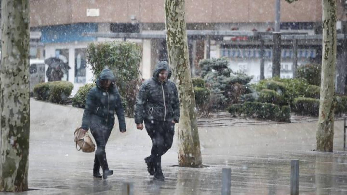 Dos personas se resguardan de la nieve esta mañana en León