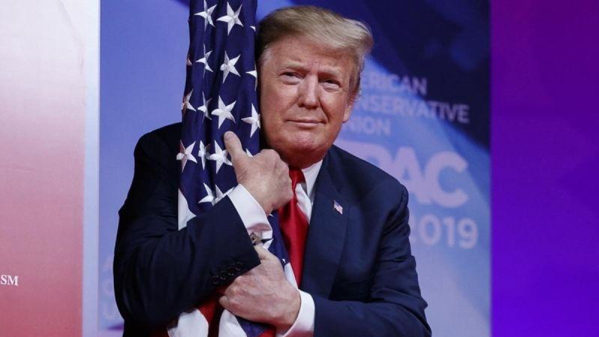 El presidente Donald Trump abraza la bandera de Estados Unidos en la Conferencia de Acción Política Conservadora.