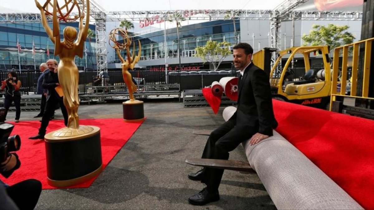 El presentador de la gala, Jimmy Kimmel, posa para la prensa, sentado sobre la alfombra roja de los 68º premios Emmy, aún enrollada.