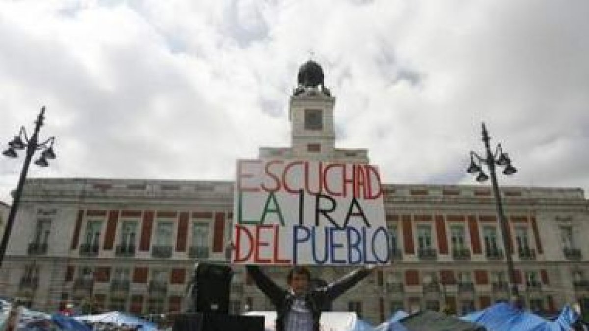 Un hombre sostiene un cartel que reza «Escuchad la ira del pueblo» en Sol.