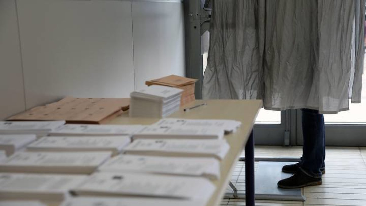 Un ciudadano ejerce su derecho al voto en la cabina junto a la mesa en la que se depositan las papeletas de todos los partidos. ANA ESCOBAR