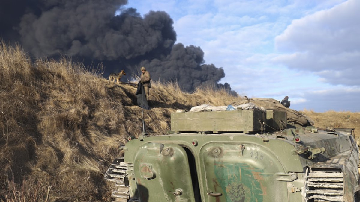 Los militares ucranianos descansan en una posición mirando el humo de un depósito de almacenamiento de petróleo quemado detrás después de que un misil ruso atacara cerca de Kiev. ALISA YAKUBOVYCH - EFE