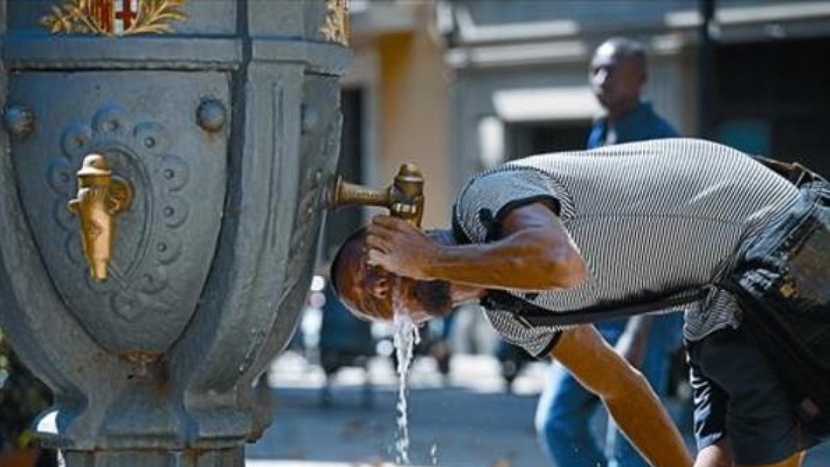 Un joven bebe agua en una fuente pública de Barcelona.