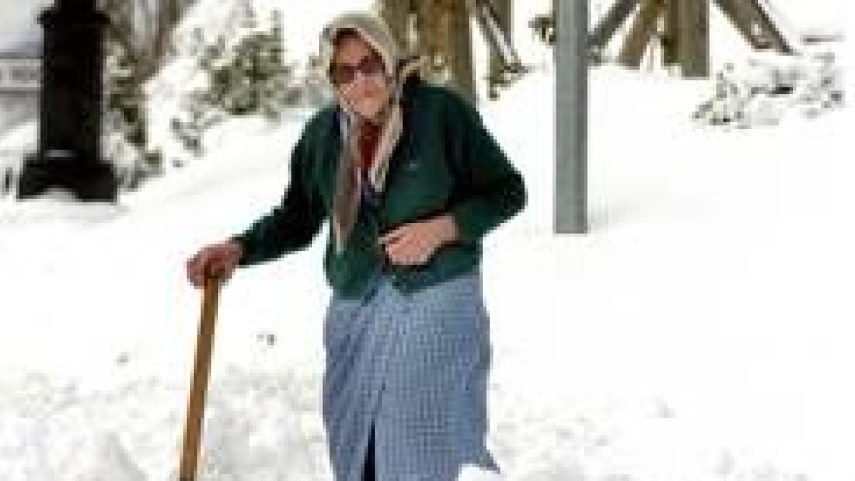 Una anciana camina con su pala tratando de abrir camino en los alrededores de su casa en Pajares