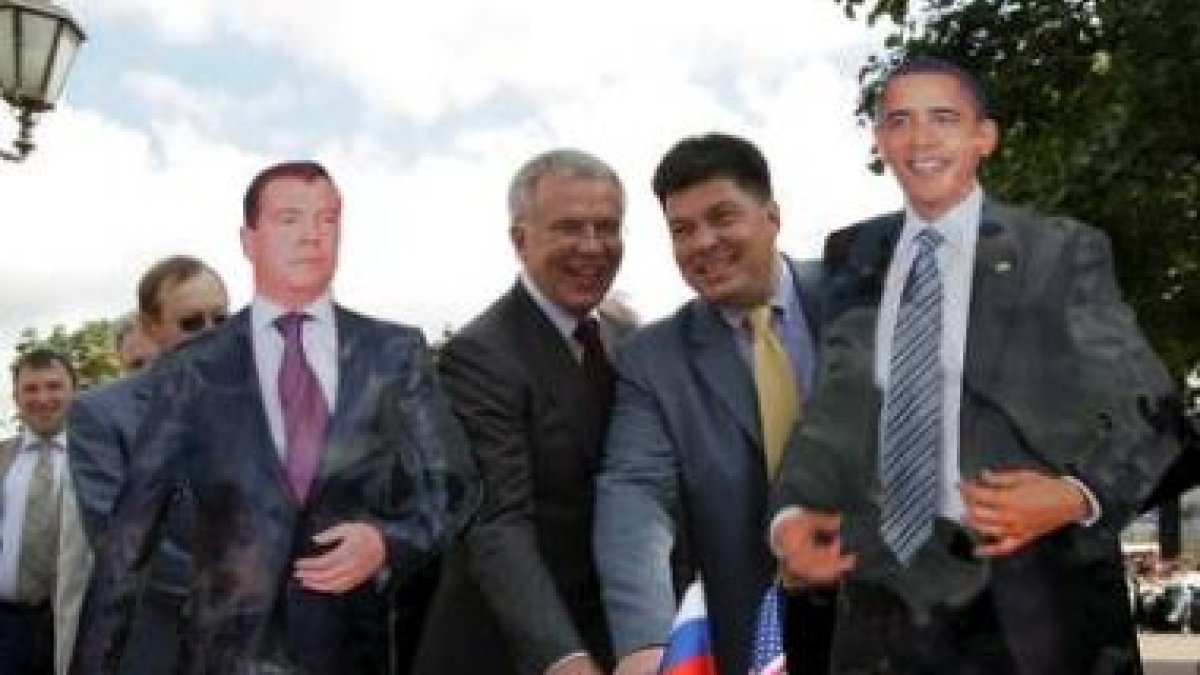 Ciudadanos rusos de fotografían con dos imágenes de Medédev y Obama.