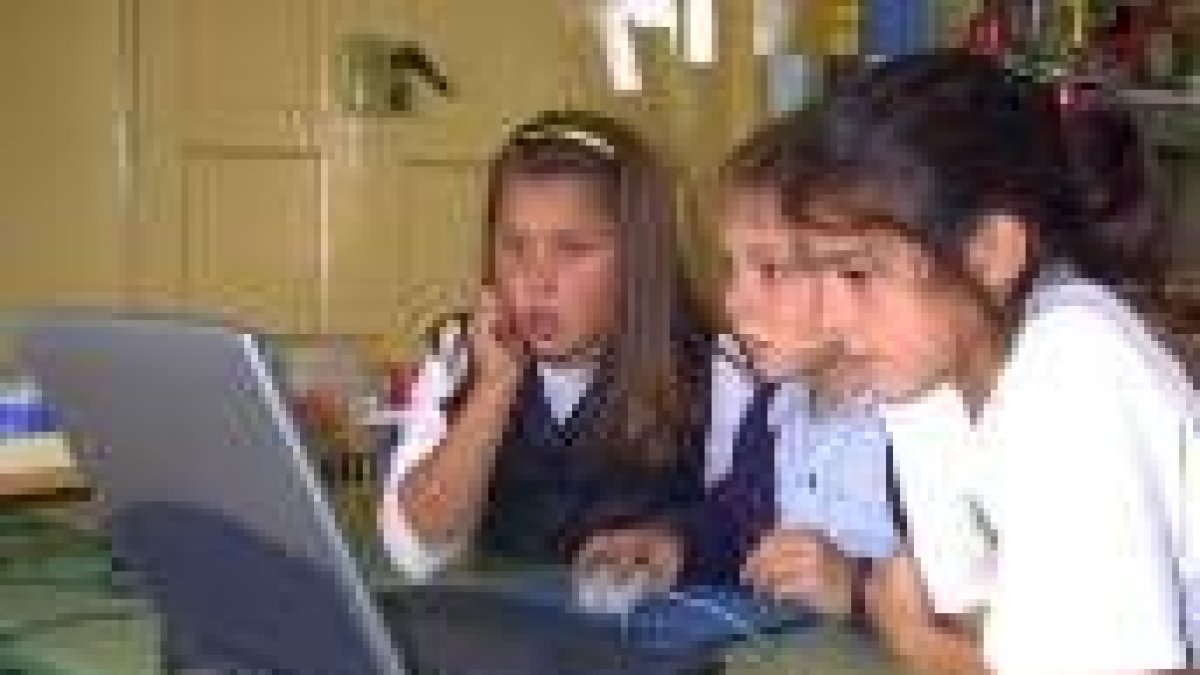 Unos niños emplean el odenador para navegar en Internet