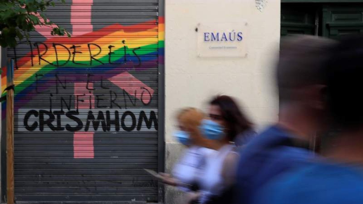 Varias personas pasan delante de una pintada contra el movimiento LGTBI en Chueca, ayer. FERNANDO ALVARADO