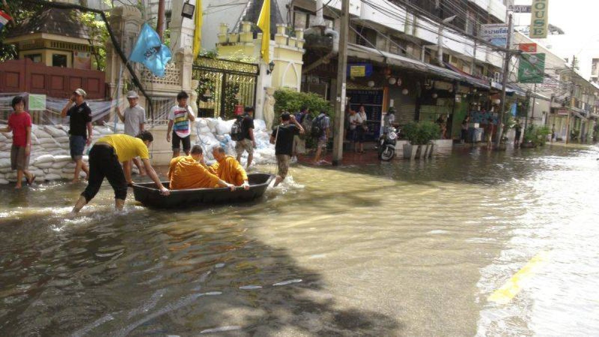 Dos monjes transportados en barca por una calle de Bangkok, la metrópoli por la que avanza la tromba de agua que anega la meseta central de Tailandia.