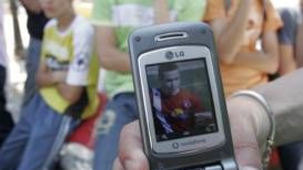Los amigos de Adrián muestran una de sus fotos en un móvil