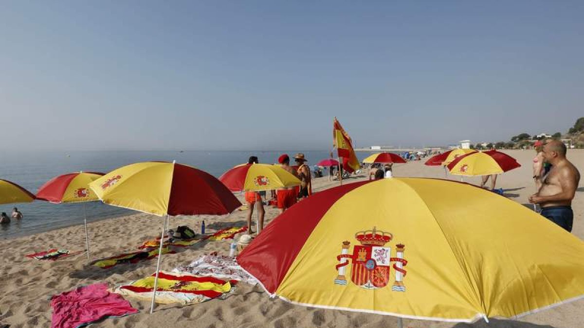 Sombrillas con los colores de la bandera de España en la playa de Arenys de Mar para contrarrestar las cruces y lazos. ANDREU DALMAU