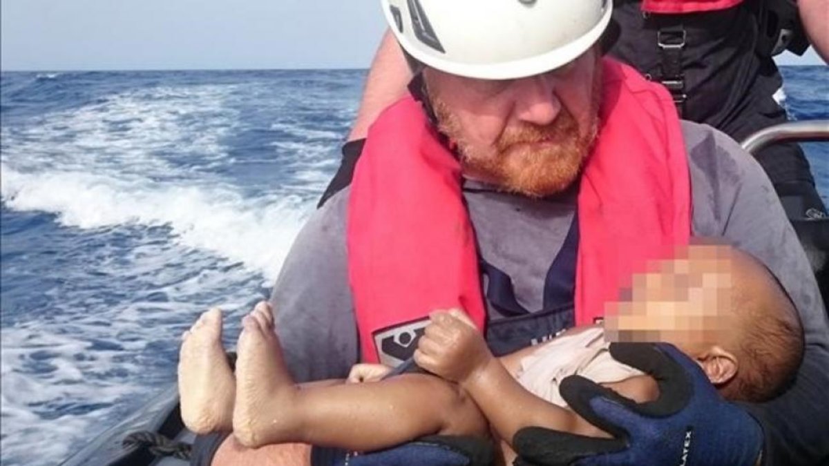 Un miembrod de la oenegé Sea Watch sostiene el cadáver de un bebé muerto recuperado de las aguas del Mediterráneo entre Libia e Italia.