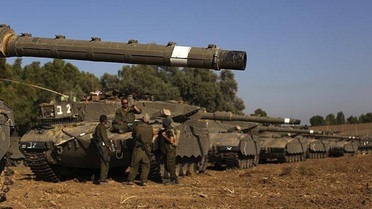 Varios soldados israelíes de una unidad de reserva, se reúnen en torno a sus tanques Markova, en la franja de Gaza, al sur de Israel.