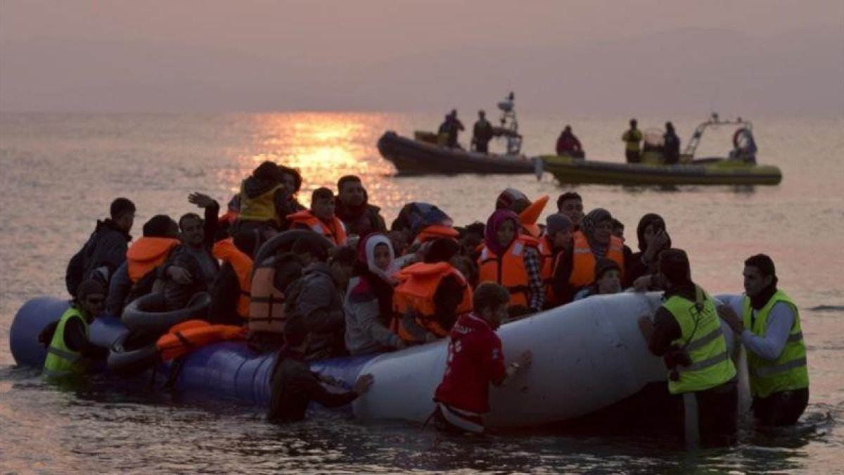 Varios voluntarios ayudan a refugiados a su llegada en un atestado bote neumático a Lesbos, el 20 de marzo.