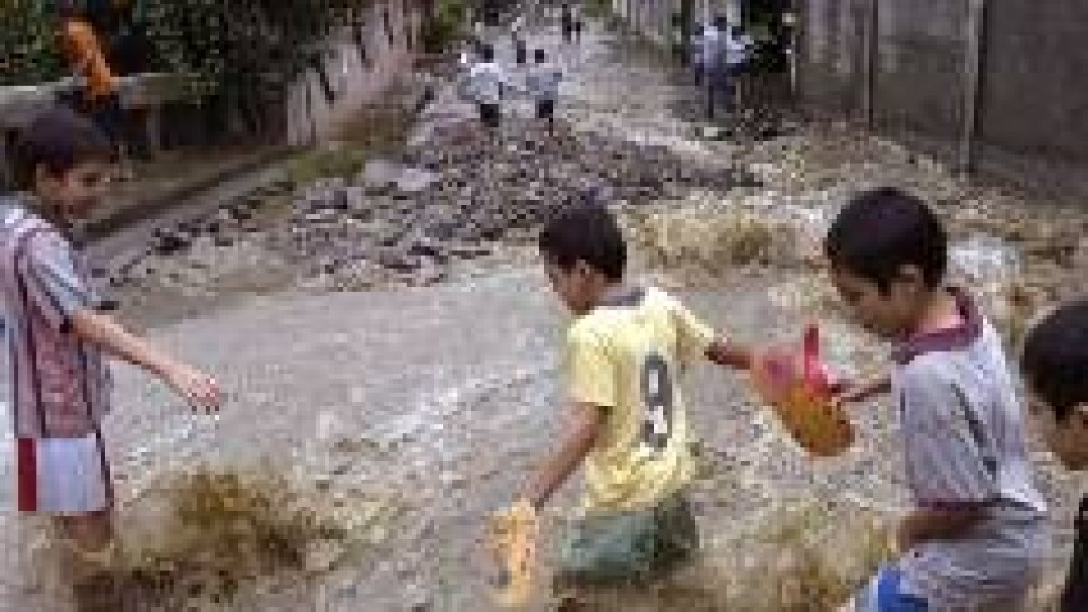 Niños hondureños cruzan una calle inundada en una colonia popular de la ciudad de San Pedro Sula